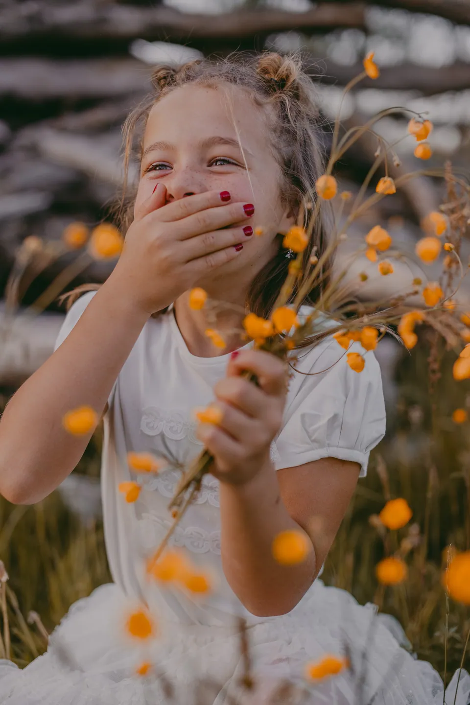Communicantje met gele bloemen voor haar mond