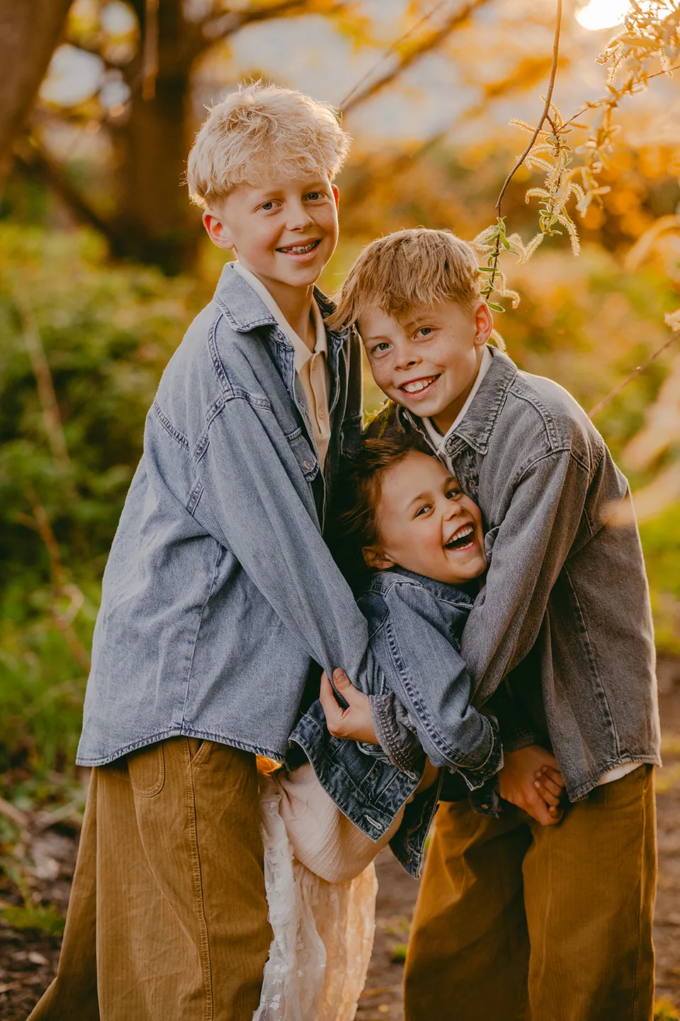 Drie kinderen in een stevige knuffel in het gouden licht