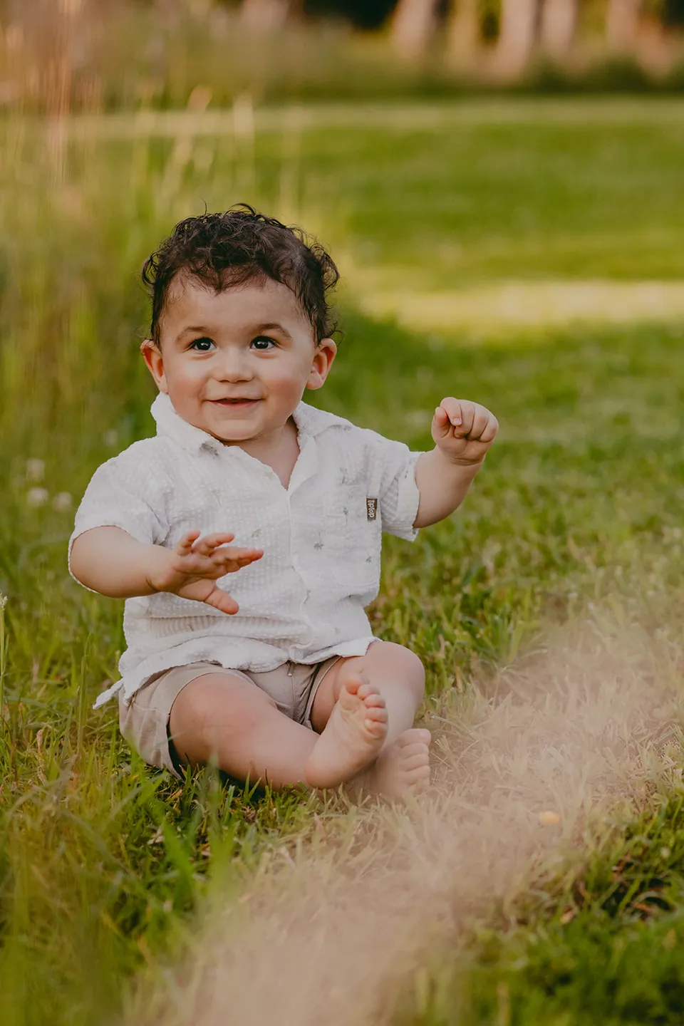 Baby zit in het hoge gras en strekt zijn handjes uit
