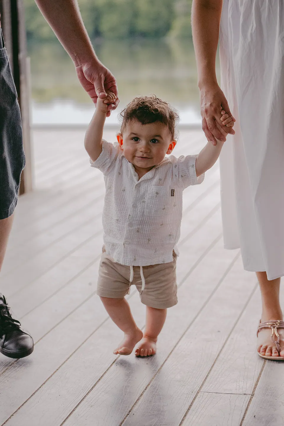 Peuter zet zijn eerste stapjes aan de handen van zijn ouders